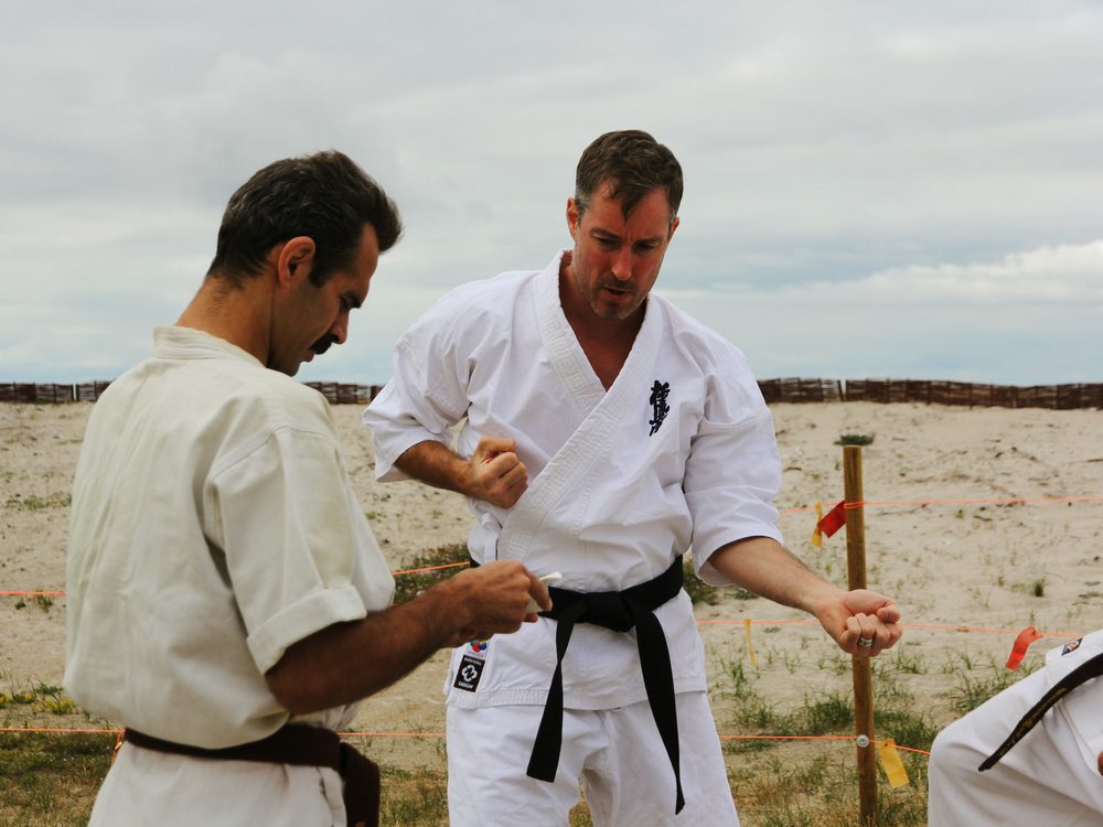 En instruktör som rättar en annan karatekas handställning